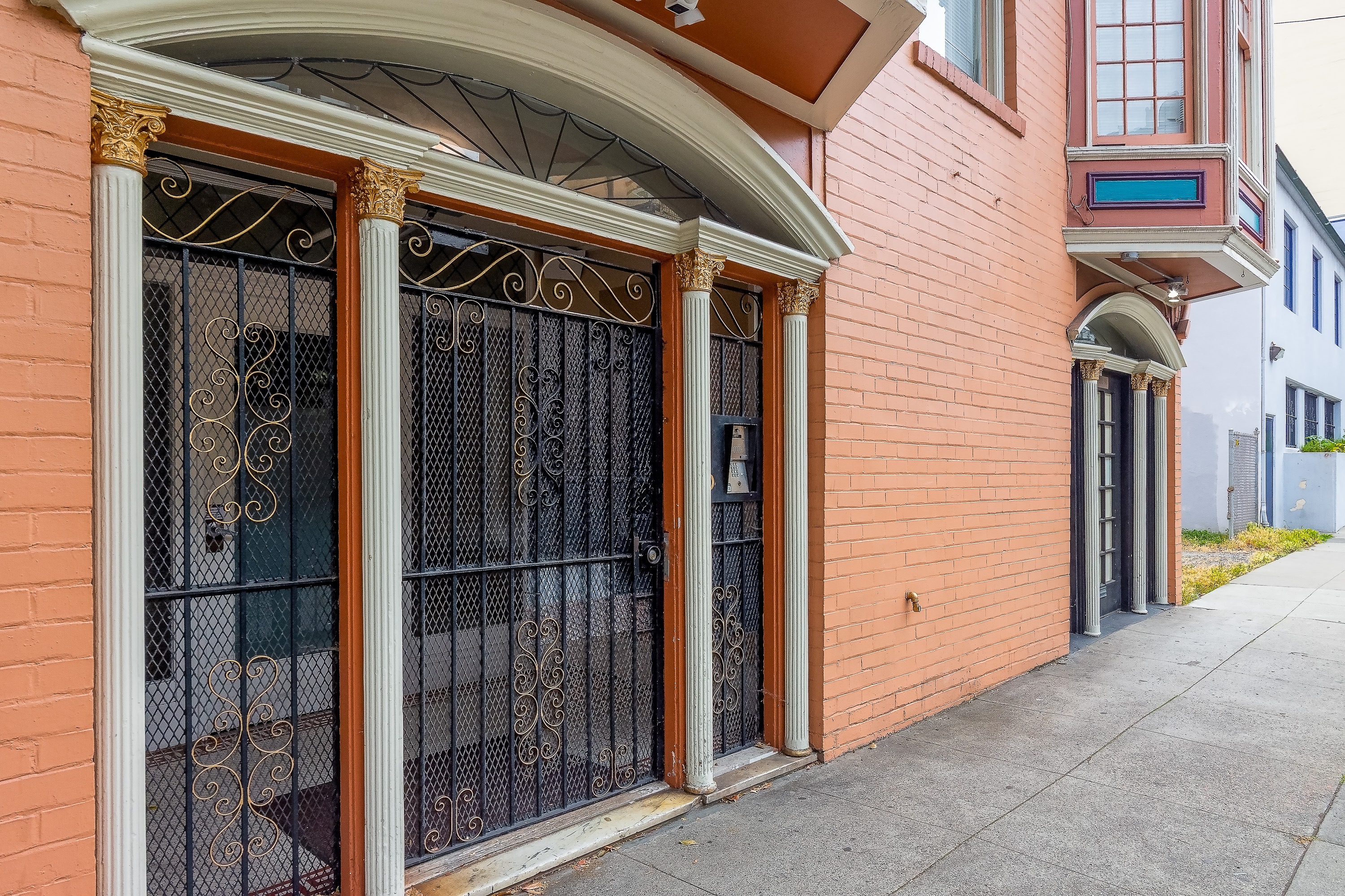 A red building with a black gate and a brown door.